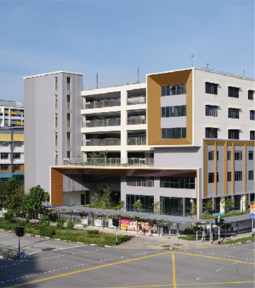 Modern building with mixed grey, white, and gold facades, near a street intersection with pedestrian crossing.